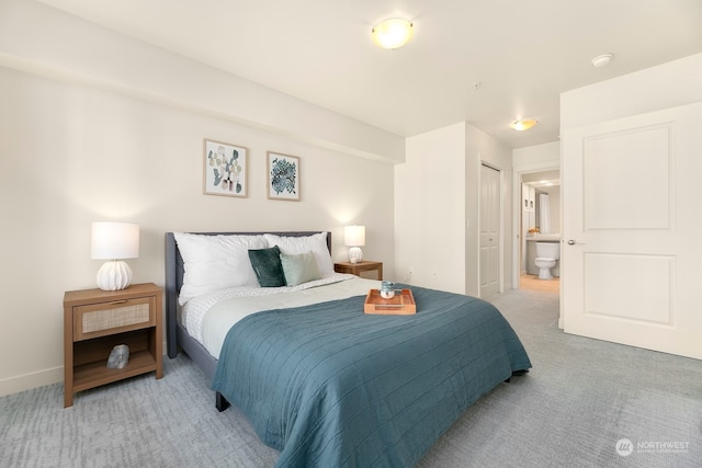 bedroom with connected bathroom, a closet, and light colored carpet