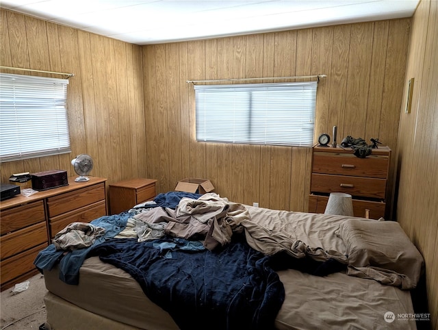 bedroom with light carpet and wooden walls