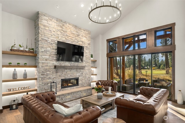 living room with a fireplace, a chandelier, light hardwood / wood-style flooring, and high vaulted ceiling