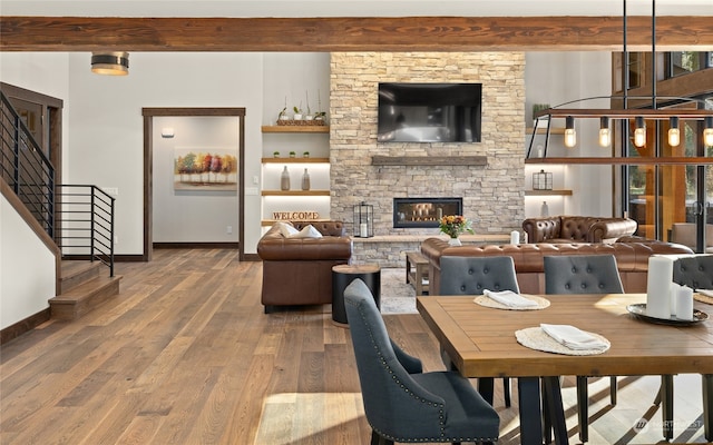 dining room featuring a fireplace, wood-type flooring, and beam ceiling