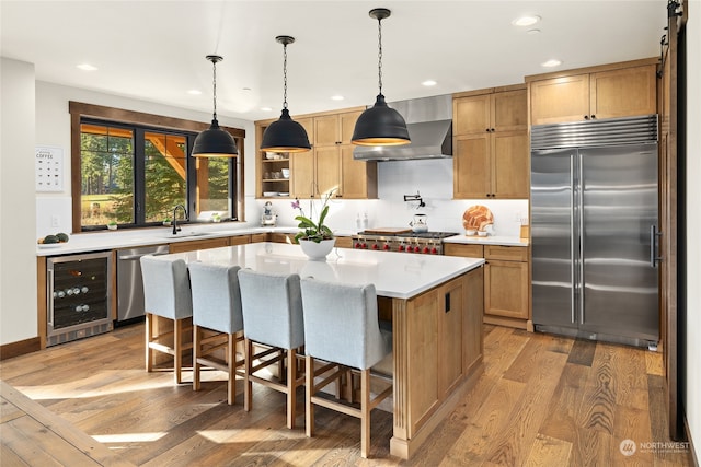 kitchen featuring light wood-type flooring, appliances with stainless steel finishes, a kitchen island, and wine cooler