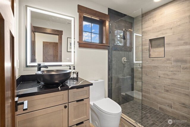 bathroom with toilet, an enclosed shower, and vanity