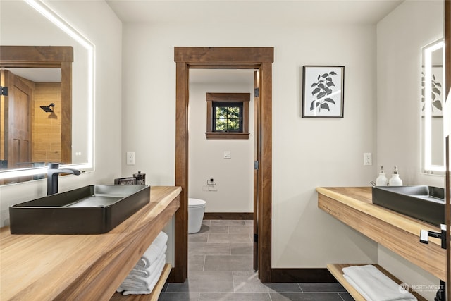 bathroom featuring toilet, a shower, sink, and tile patterned floors