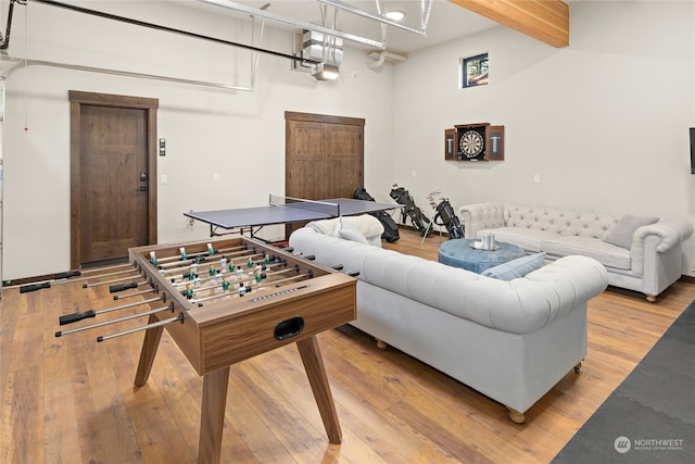 game room featuring light hardwood / wood-style floors and beam ceiling