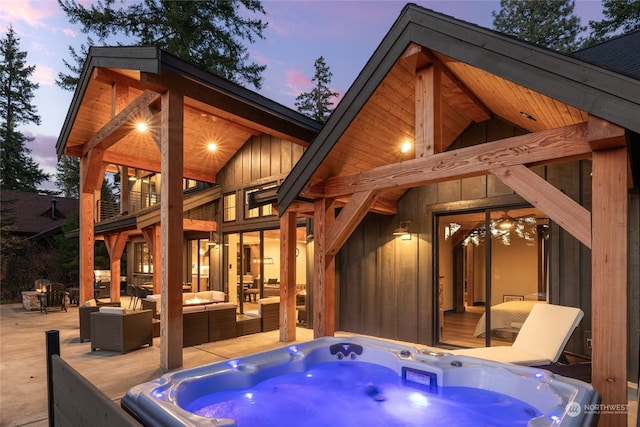 back house at dusk featuring a hot tub and an outdoor living space