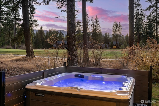 pool at dusk with a hot tub