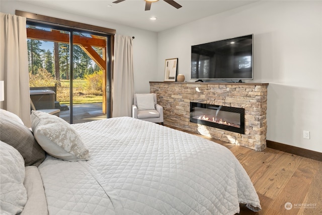 bedroom featuring a fireplace, wood-type flooring, ceiling fan, and access to outside