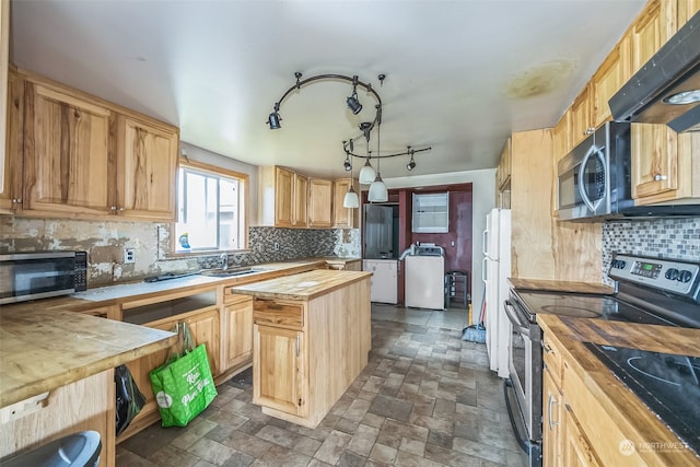 kitchen with pendant lighting, backsplash, butcher block counters, stainless steel appliances, and washer / clothes dryer