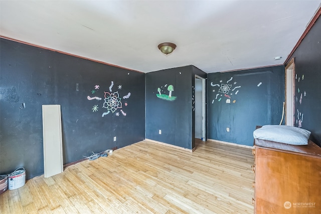 unfurnished bedroom with ornamental molding and light wood-type flooring