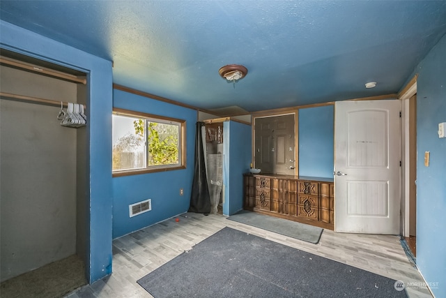 bathroom featuring crown molding, wood-type flooring, and a textured ceiling