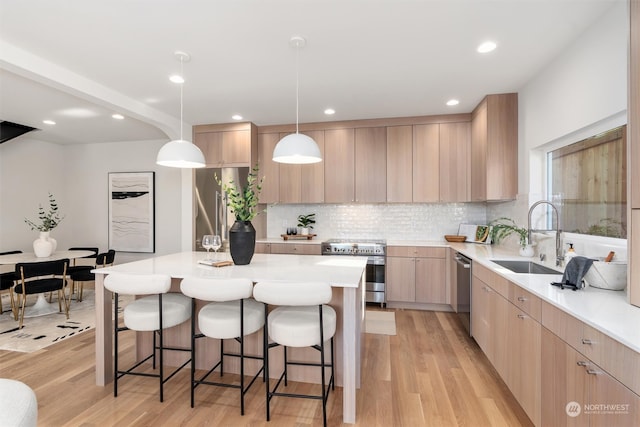 kitchen with stainless steel appliances, sink, light hardwood / wood-style flooring, and light brown cabinets