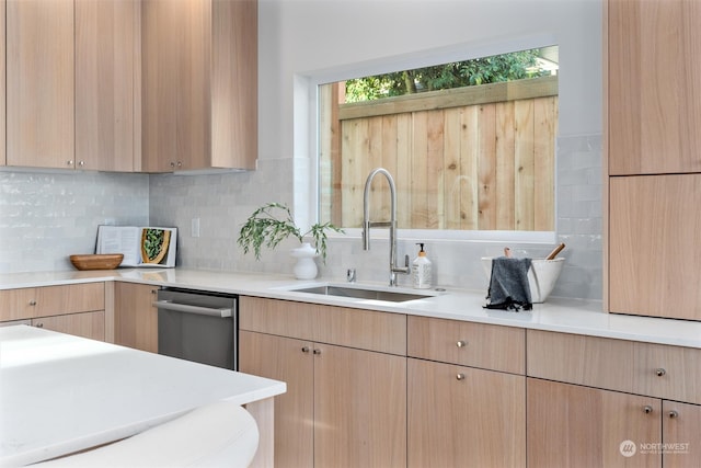 kitchen featuring light brown cabinets, stainless steel dishwasher, decorative backsplash, and sink