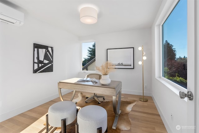 home office with a wall unit AC and light hardwood / wood-style floors