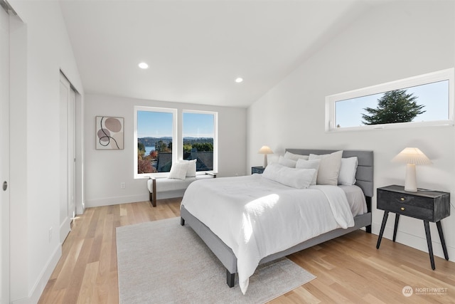 bedroom featuring multiple windows, lofted ceiling, and light hardwood / wood-style flooring