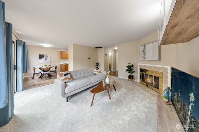 living room with light wood-type flooring and a tile fireplace