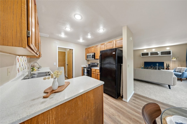 kitchen featuring black appliances, sink, and light hardwood / wood-style floors