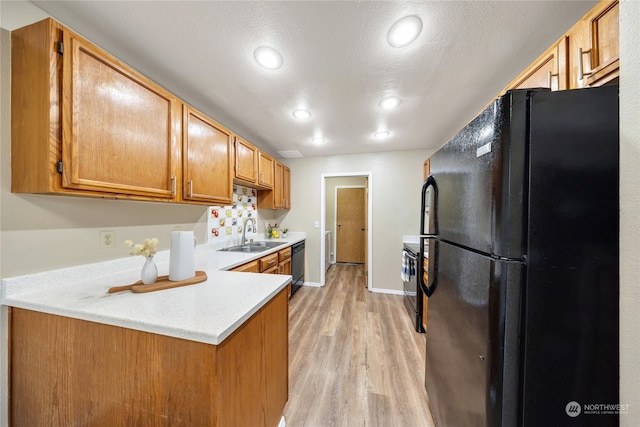 kitchen featuring light hardwood / wood-style floors, sink, black appliances, kitchen peninsula, and a textured ceiling