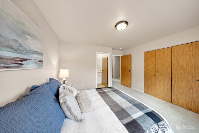 carpeted bedroom with ensuite bathroom and a closet