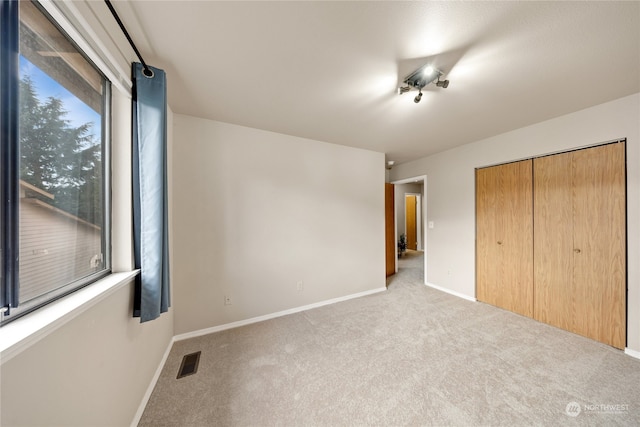 unfurnished bedroom with a closet and light colored carpet