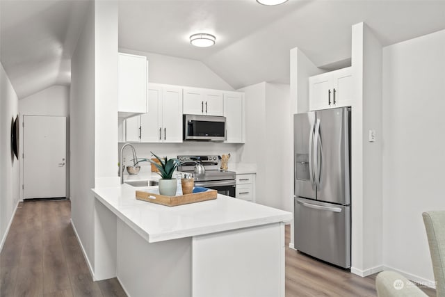 kitchen with white cabinetry, appliances with stainless steel finishes, vaulted ceiling, and light hardwood / wood-style floors