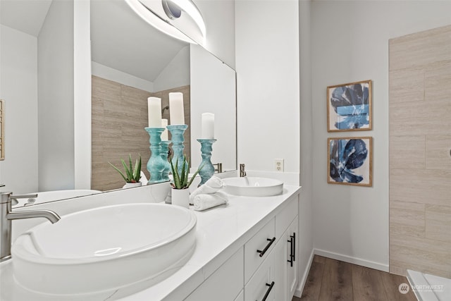 bathroom featuring vanity, hardwood / wood-style flooring, and vaulted ceiling