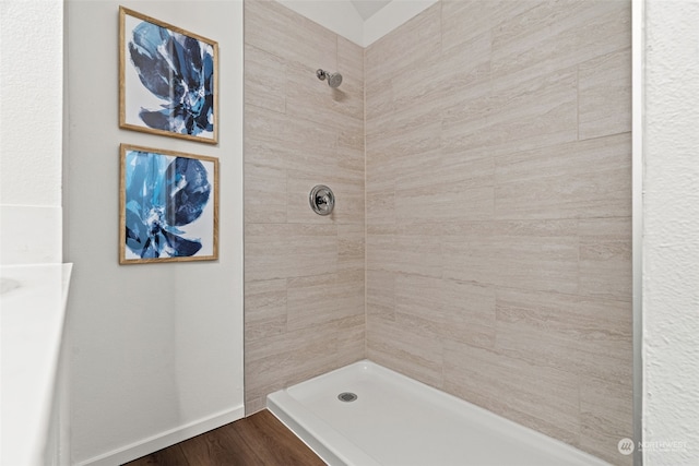 bathroom featuring hardwood / wood-style flooring and a tile shower