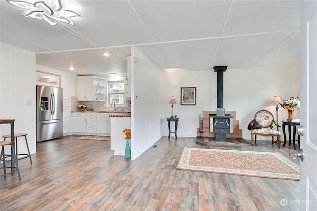 living room with sink, a wood stove, and wood-type flooring