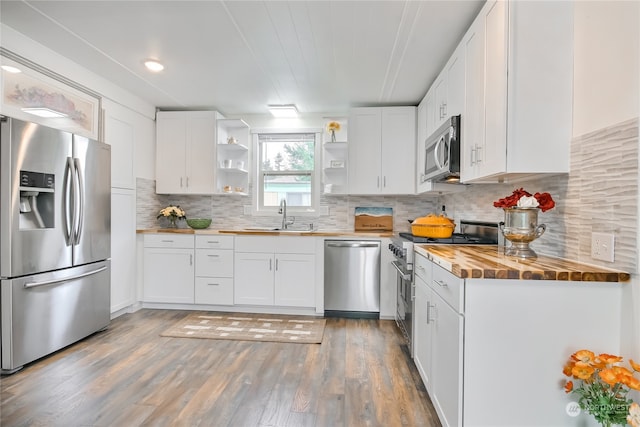 kitchen featuring stainless steel appliances, wood counters, white cabinets, and hardwood / wood-style floors