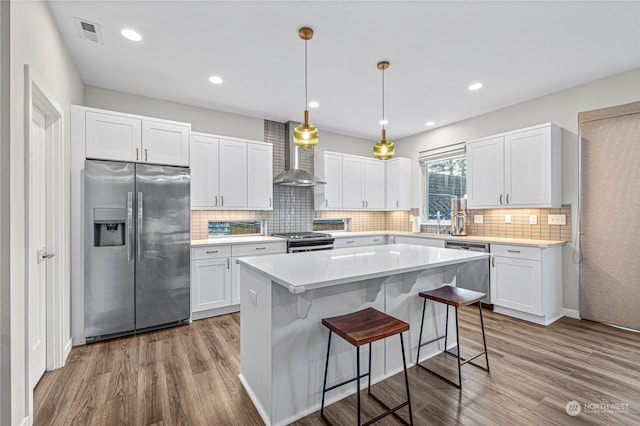 kitchen featuring light hardwood / wood-style flooring, white cabinetry, wall chimney exhaust hood, and stainless steel appliances