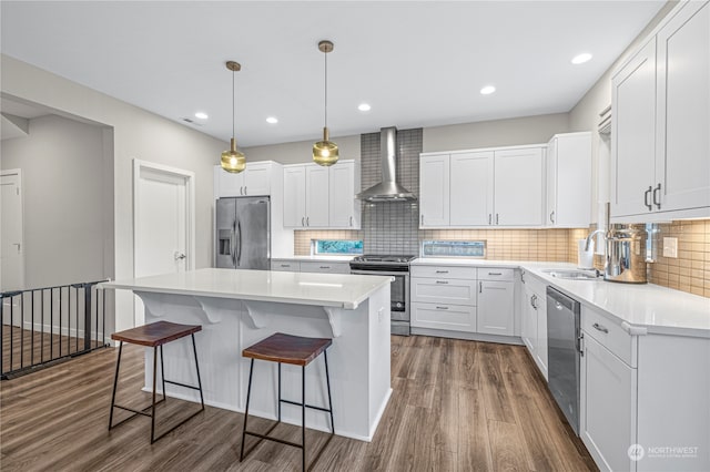 kitchen with stainless steel appliances, dark hardwood / wood-style floors, sink, white cabinets, and wall chimney exhaust hood