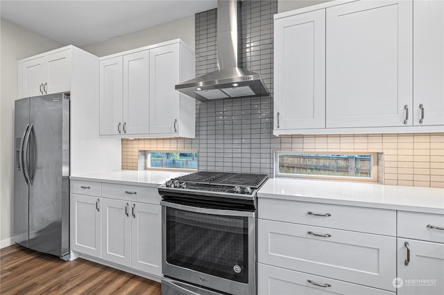 kitchen with stainless steel appliances, wall chimney exhaust hood, dark hardwood / wood-style floors, white cabinets, and decorative backsplash