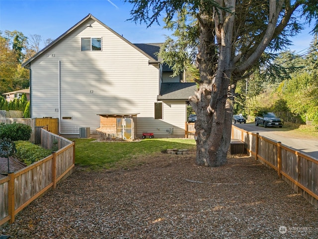 back of property featuring central air condition unit and a yard