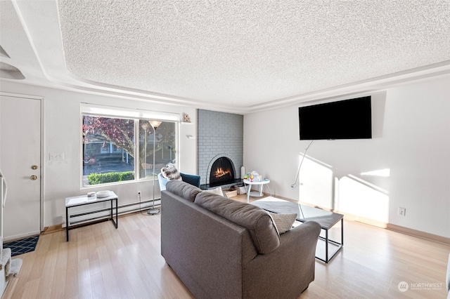 living room with a brick fireplace, a textured ceiling, light hardwood / wood-style flooring, and a baseboard heating unit