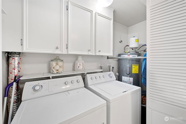 laundry room featuring electric water heater, a textured ceiling, cabinets, and washer and clothes dryer