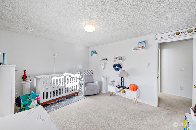 bedroom featuring a textured ceiling, carpet floors, and a crib