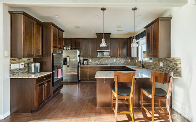 kitchen with hanging light fixtures, decorative backsplash, stainless steel appliances, and dark wood-type flooring