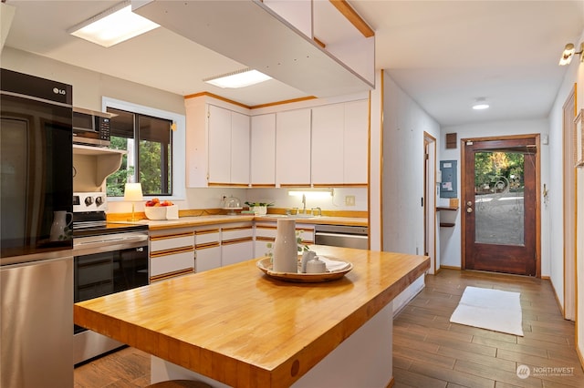 kitchen with stainless steel appliances, dark hardwood / wood-style floors, white cabinetry, and a kitchen island