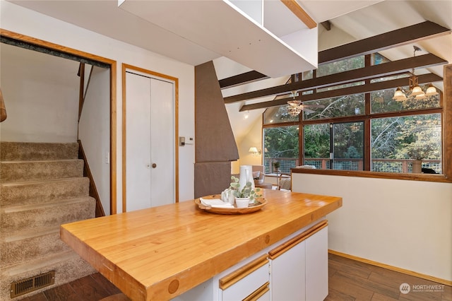 dining area featuring ceiling fan, vaulted ceiling with beams, and dark hardwood / wood-style flooring