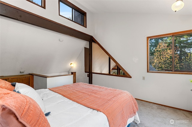 bedroom featuring multiple windows, lofted ceiling, and carpet flooring