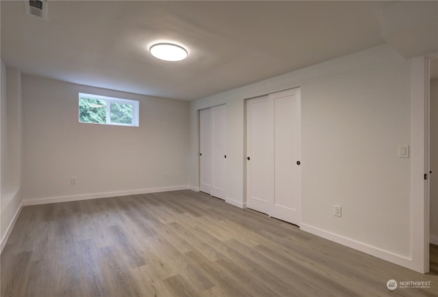 unfurnished bedroom featuring light hardwood / wood-style flooring and two closets