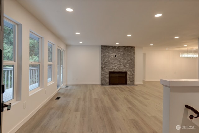 unfurnished living room with a stone fireplace and light wood-type flooring