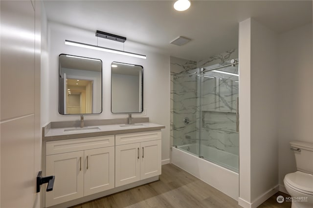 full bathroom with bath / shower combo with glass door, wood-type flooring, vanity, and toilet