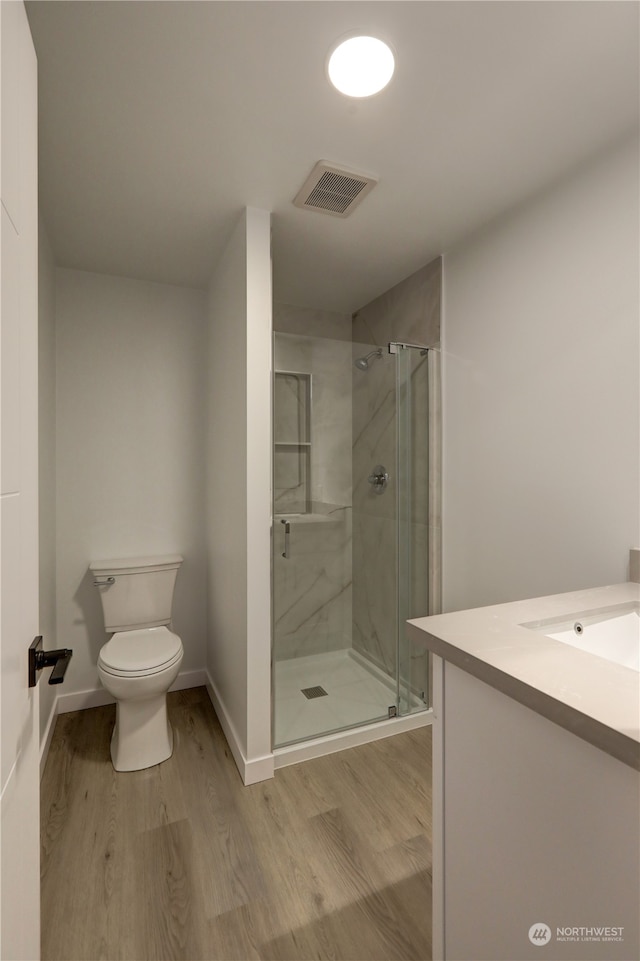 bathroom featuring walk in shower, wood-type flooring, toilet, and vanity