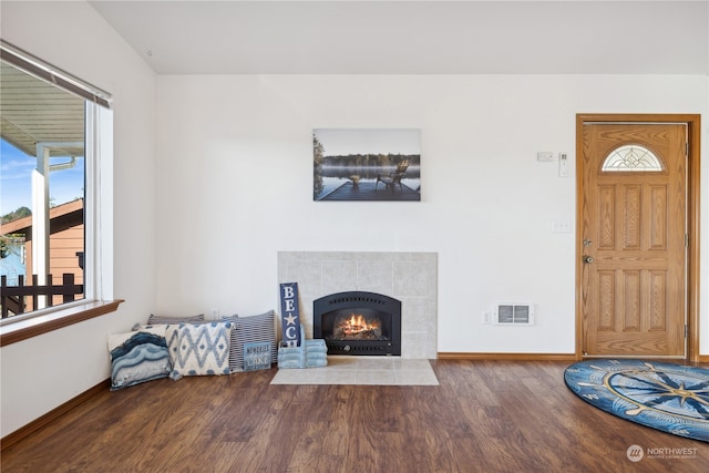 living room with a fireplace, wood finished floors, visible vents, and baseboards