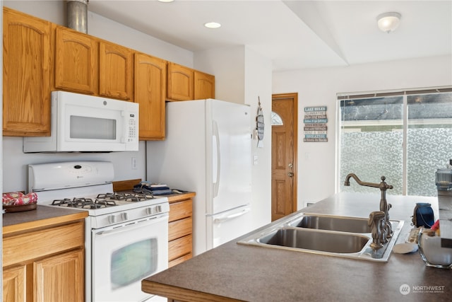 kitchen featuring white appliances, recessed lighting, dark countertops, and a sink