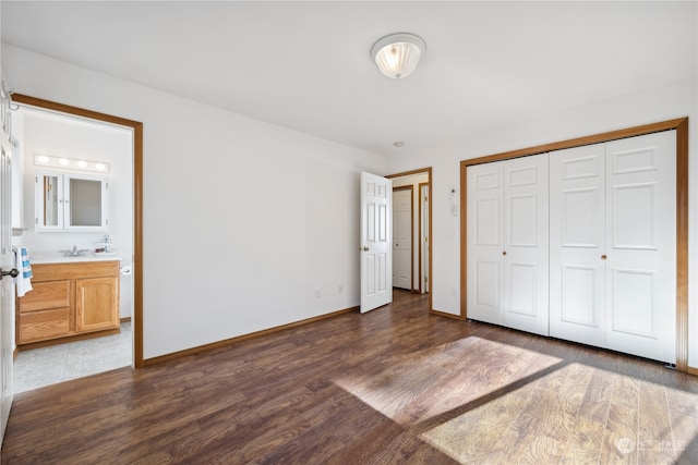 unfurnished bedroom featuring a closet, dark wood-type flooring, baseboards, and a sink