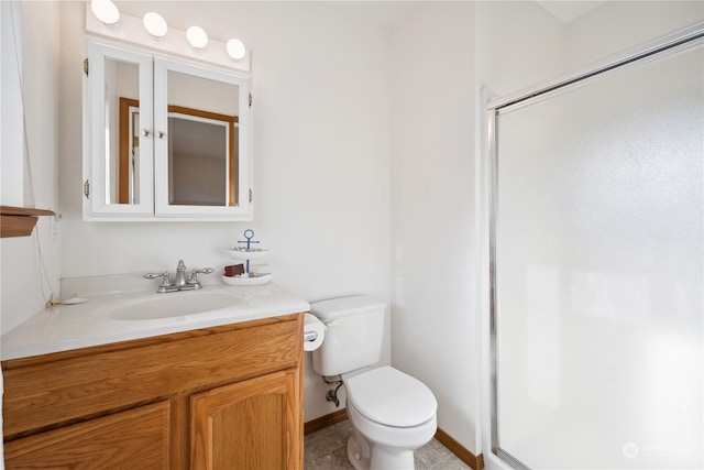 bathroom with a shower stall, toilet, vanity, and baseboards
