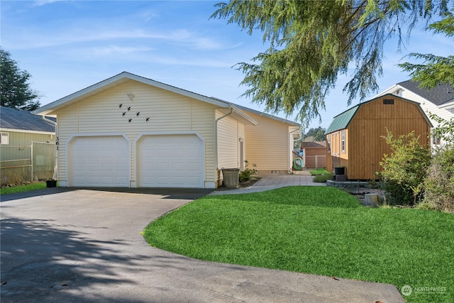 view of front facade with a detached garage, an outdoor structure, a front lawn, and fence