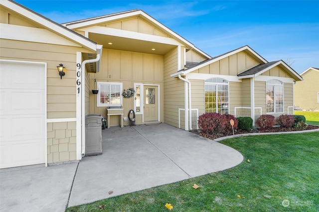 doorway to property with a garage and a yard