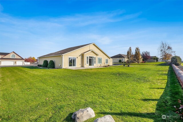 back of property with a garage and a lawn